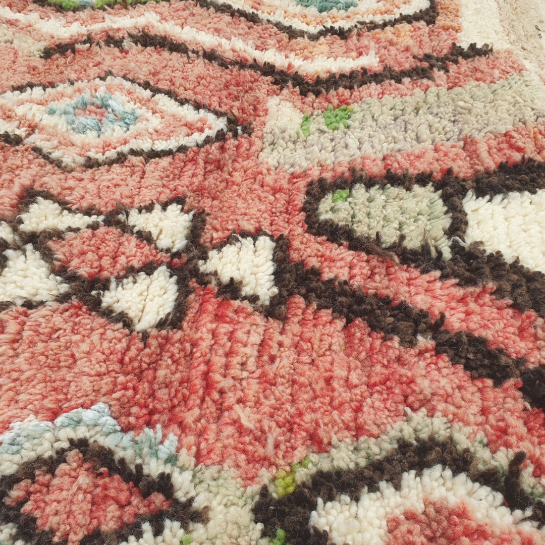 Close-up of a Bizri Moroccan rug showing the soft wool pile with the cream diamond lattice pattern - the outlined diamonds forming a continuous trellis against the terracotta ground, with orange and teal lozenges visible, handwoven in 100% wool