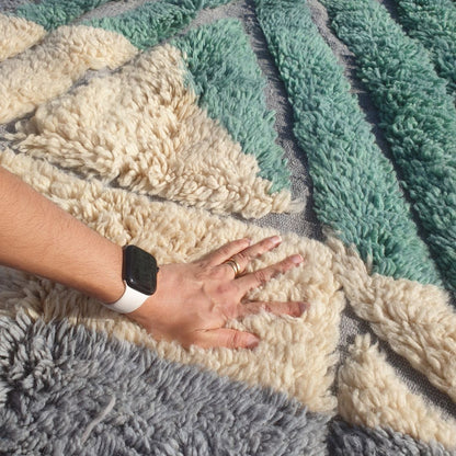 Close-up of a luxurious Beni Mrirt Moroccan rug showing the exceptional depth and softness of the high-density wool pile — intricate teal green geometric diamond shapes on cream ivory wool with subtle grey lavender triangular sections, the extraordinary plush texture of authentic Beni Mrirt craftsmanship