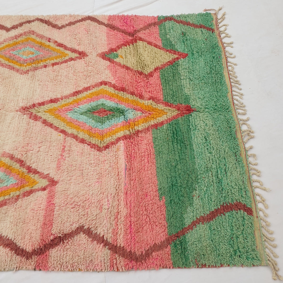 Detail shot of the colour-block transition on Kasma Moroccan rug - the blush pink field meeting the solid jade green band, with the brown zigzag border line visible along the edge

