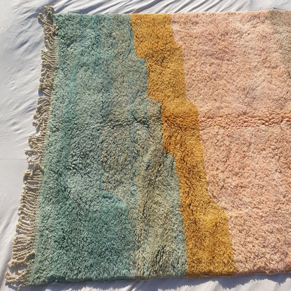Bottom half of a luxury Beni Mrirt Moroccan wool rug showing the warm salmon and dusty rose dominant lower field with exceptionally thick plush pile and natural hand-knotted fringe — the watercolor-like color transitions showcase