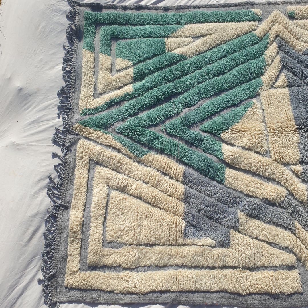 Bottom half of a luxury Beni Mrirt Moroccan rug featuring rich teal green geometric diamond patterns on a cream ivory background with soft grey accents, an exceptionally thick handknotted high-pile wool surface with natural fringe — showcasing the remarkable density that defines Beni Mrirt as Morocco's most luxurious rug