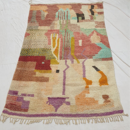 Authentic Moroccan rug 195x321 cm laid flat outdoors - predominantly ivory ground with a soft muted pastel abstract patchwork and purple accent details, handwoven in Morocco, the longest rug in our current collection