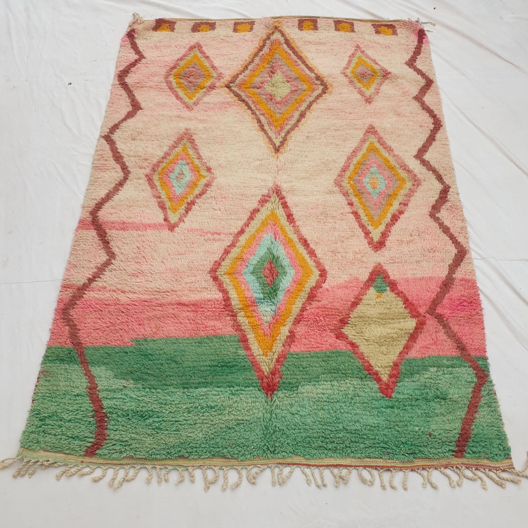 Authentic Moroccan rug 194x293 cm laid flat outdoors - bold pink and jade green colour-block design with stacked concentric diamond medallions in yellow, orange and mint, handwoven in Morocco