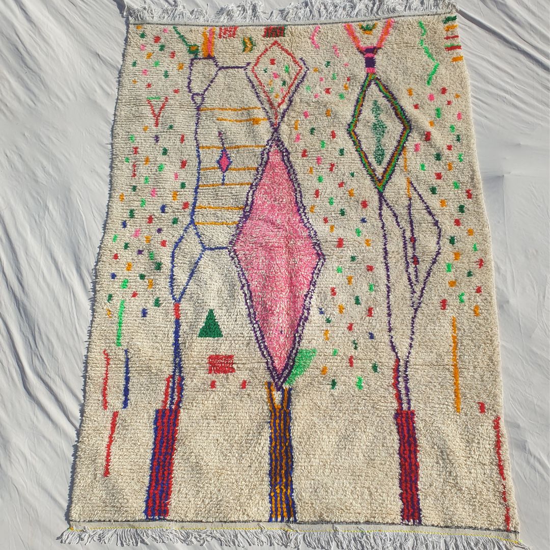 Authentic Azilal Moroccan rug 195×282 cm laid flat — cream white natural wool base with scattered multicolor confetti dots, large central rose-pink diamond, two elongated purple diamond outlines, green outlined upper diamonds and bold navy/red vertical accent lines, handwoven in Morocco by Azilal Berber women