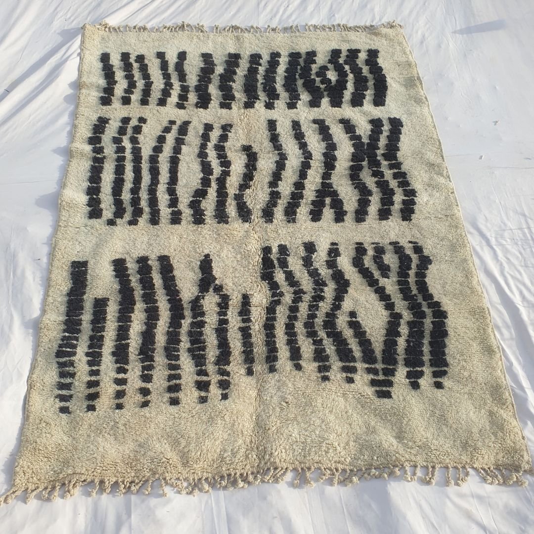 Full view of 7x10 Beni Mrirt rug with fringed edges and all-over black and white geometric pattern showing traditional craftsmanship