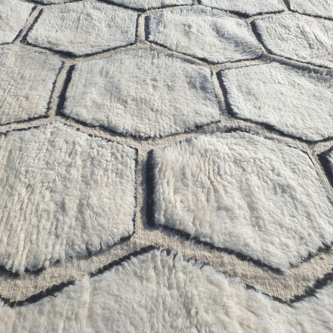 Intricate repeating honeycomb hexagon pattern outlined in bold black on authentic Beni Ourain wool rug, showcasing traditional Berber geometric design