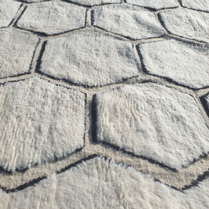 Intricate repeating honeycomb hexagon pattern outlined in bold black on authentic Beni Ourain wool rug, showcasing traditional Berber geometric design