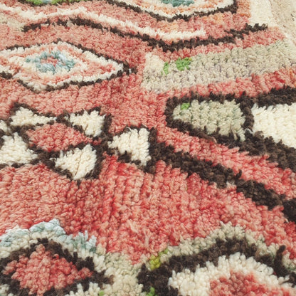 Close-up of a Bizri Moroccan rug showing the soft wool pile with the cream diamond lattice pattern - the outlined diamonds forming a continuous trellis against the terracotta ground, with orange and teal lozenges visible, handwoven in 100% wool