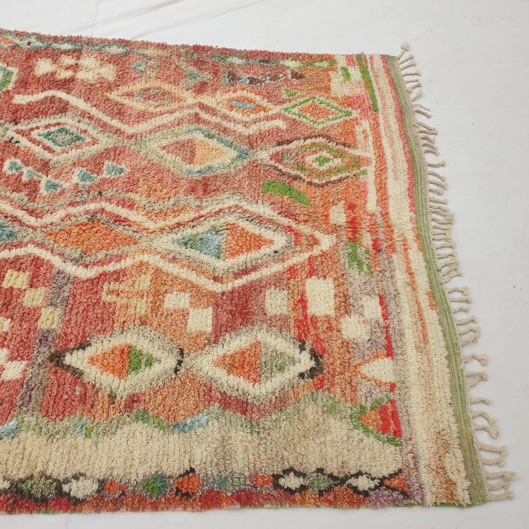 Detail shot of the diamond lattice structure on Bizri Moroccan rug - the repeating cream outline diamonds and their alternating coloured fills creating a rhythmic, classic pattern across the terracotta field