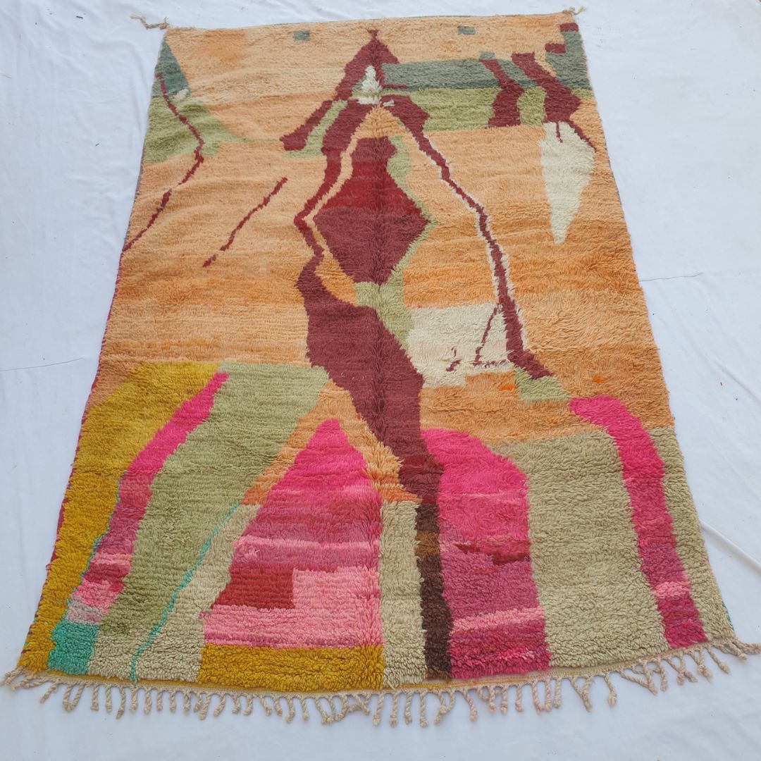 handwoven Boujad Berber rug (189x306 cm) laid flat, warm peach-orange ground with a large burgundy abstract silhouette, sage green upper bands, and bold hot pink and olive lower field.