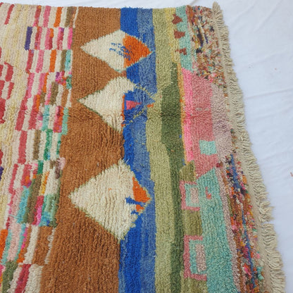 Lower half of Clahma Moroccan Berber rug displaying soft pastel pink, teal and beige abstract patches with thick, fluffy handwoven wool pile and natural fringe.
