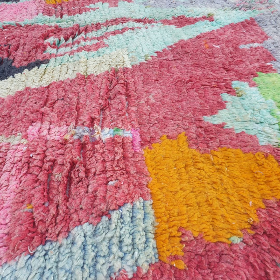 Close-up of Clala Boujad rug showing large fluid organic shapes — tall central teal feather form, bold black blobs and electric lime-green band in thick dense hand-knotted wool.