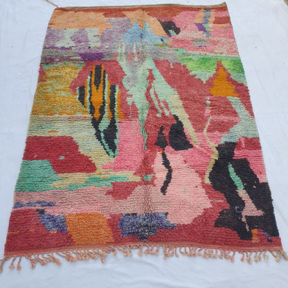 handwoven Boujad Berber rug (210x290 cm) laid flat, explosive abstract expressionist composition in coral-red with teal, black, lime green, purple and orange shapes.