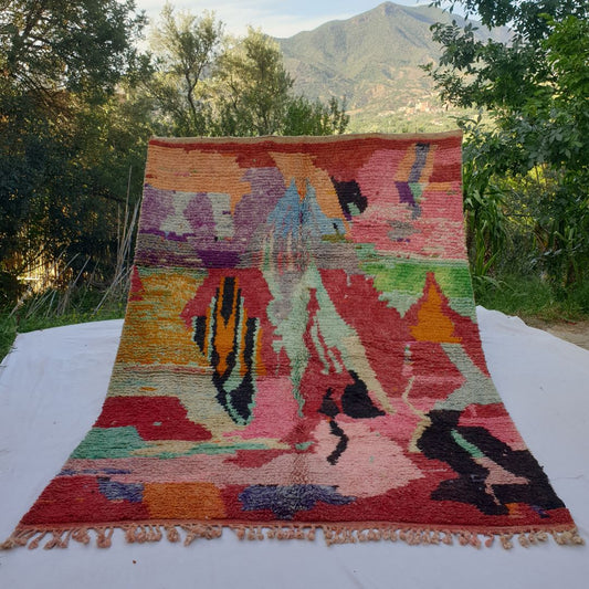 large red Boujad Moroccan rug in nature, bold painterly abstract shapes in teal, black, lime green, purple and orange on coral-red ground.