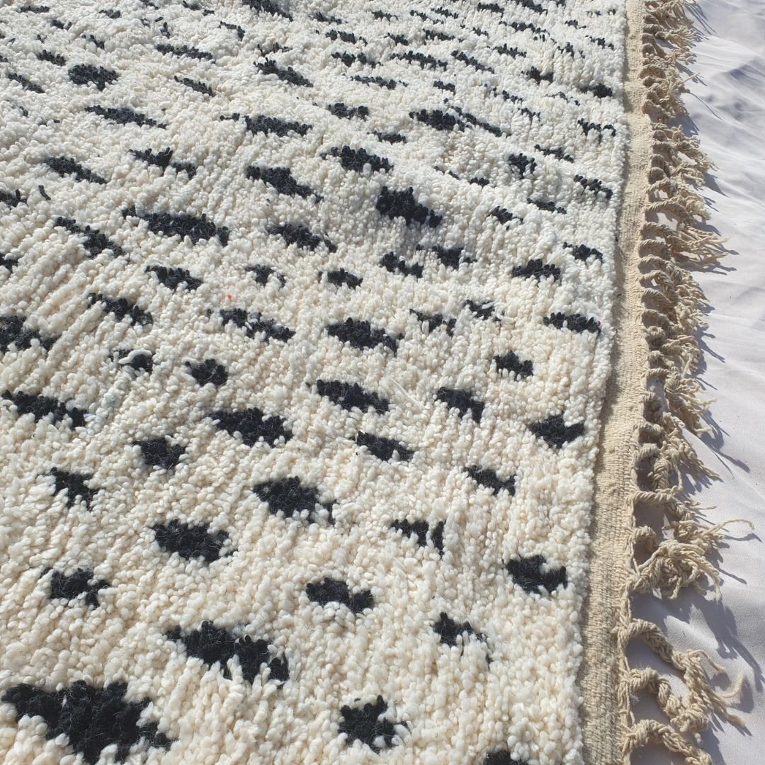 Detailed view of repeating black abstract shapes and symbols covering the white field of this Berber Boujad carpet