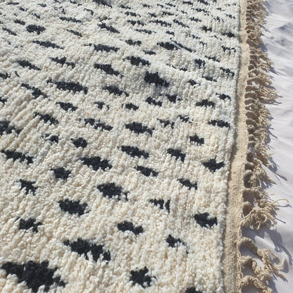Detailed view of repeating black abstract shapes and symbols covering the white field of this Berber Boujad carpet