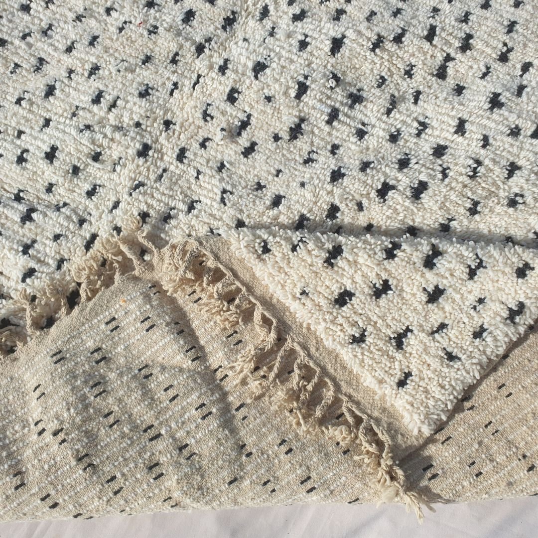 Symmetrical black geometric design with varied motifs on the natural white wool base of the Boujad rug