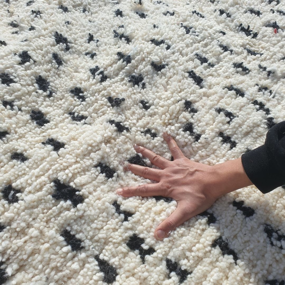 Close-up of textured wool pile and intricate black dotted geometric patterns on the handmade Boujad rug