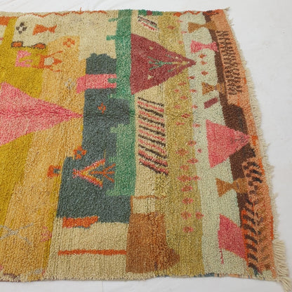 Detail shot of the storytelling motifs on Faycha Moroccan rug - small vessel and goblet-like forms, a bird figure and a deep maroon triangle with a stylised plant motif near the base of the composition
