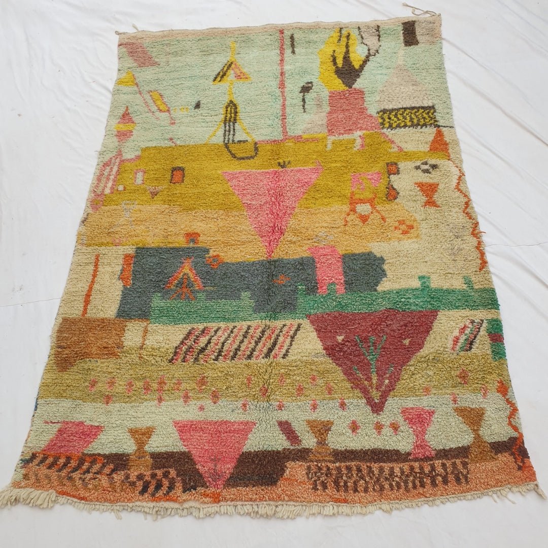 Authentic Moroccan rug 193x308 cm laid flat outdoors - mint green, mustard gold, pink and teal colour zones with a dense pictorial abstract composition and warm terracotta harlequin border, handwoven in Morocco
