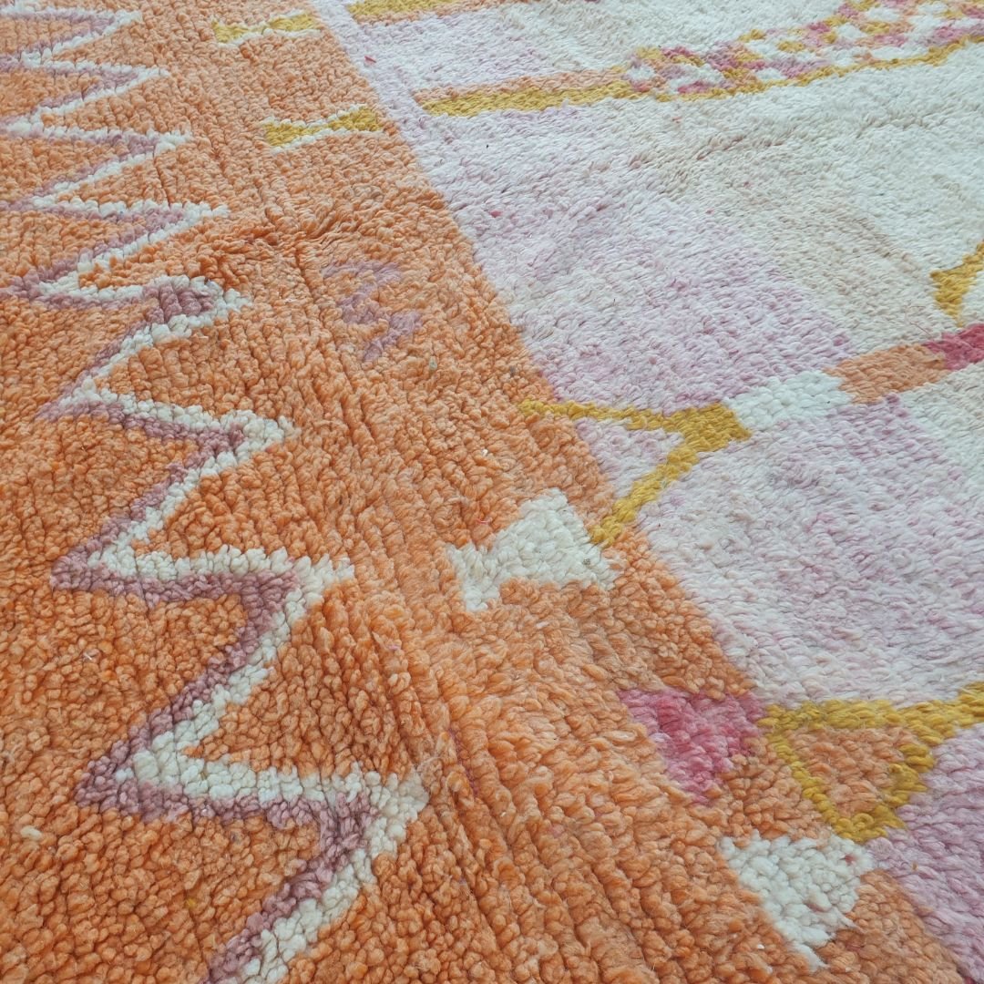 Intricate handwoven Berber tribal figures in pink, yellow and orange on beige field of authentic Boujad Moroccan rug, showing anthropomorphic dancers or guardians