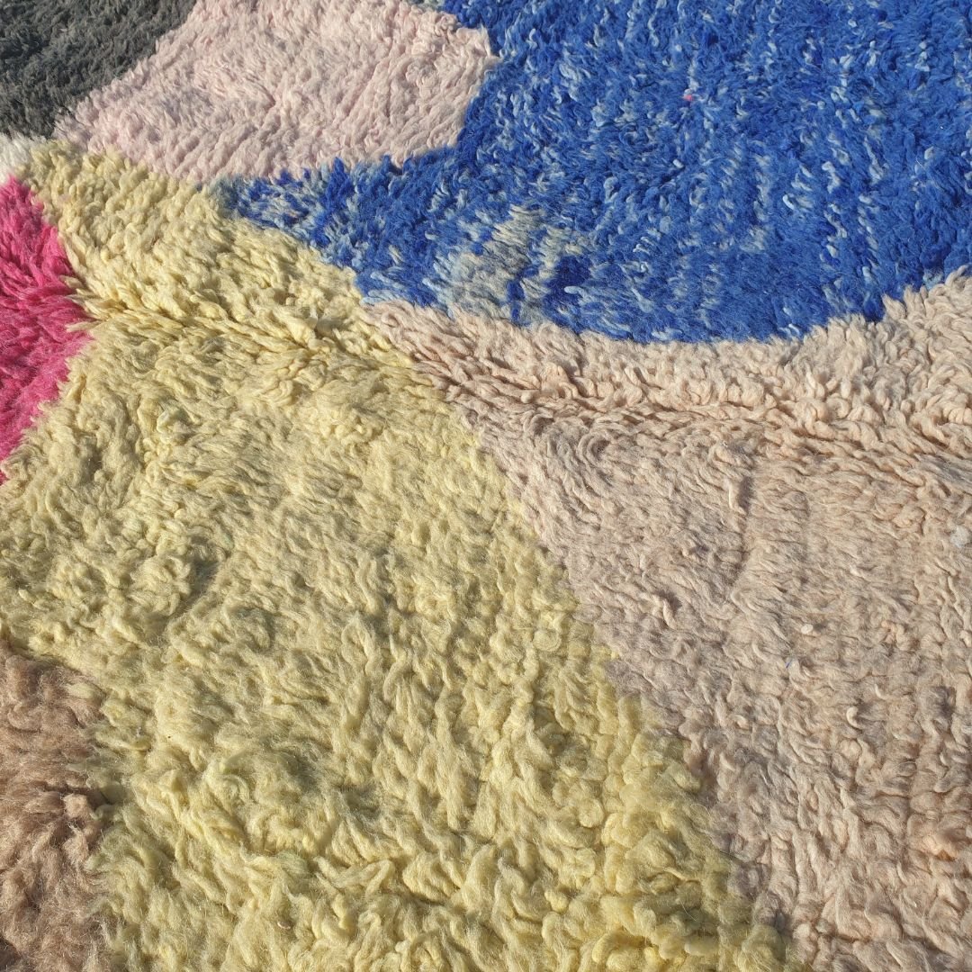 Intricate abstract blocks and angular motifs in vibrant blue, soft pink, warm orange and neutral tones on authentic Beni Ourain wool shag rug