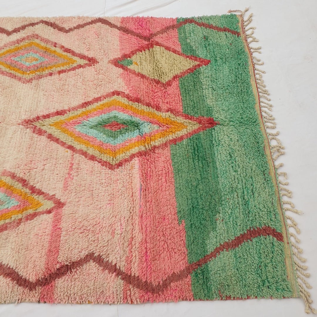 Detail shot of the colour-block transition on Kasma Moroccan rug - the blush pink field meeting the solid jade green band, with the brown zigzag border line visible along the edge
