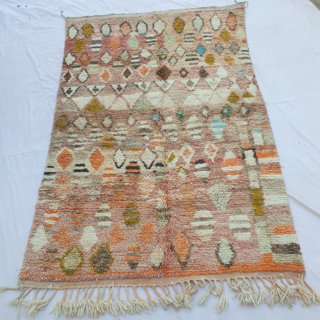 handwoven Boujaad Berber rug (188x315 cm) laid flat, warm rose-pink and terracotta ground densely covered in scattered diamond and oval tribal motifs in ivory, mustard, teal, orange and brown.