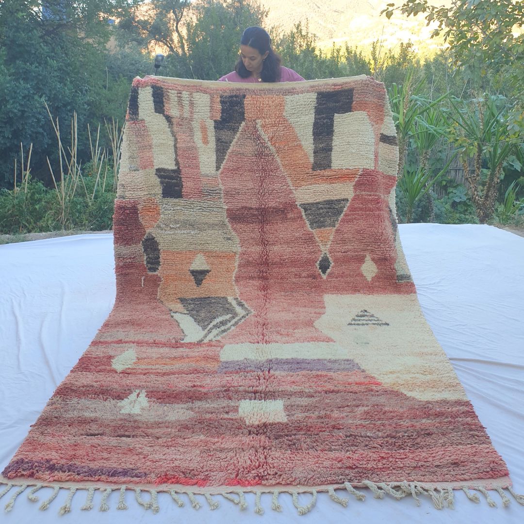 Vintage 6x9 Boujad Moroccan rug handwoven in faded red, pink, orange and cream with bold abstract Berber patterns, displayed outdoors