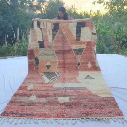 Vintage 6x9 Boujad Moroccan rug handwoven in faded red, pink, orange and cream with bold abstract Berber patterns, displayed outdoors