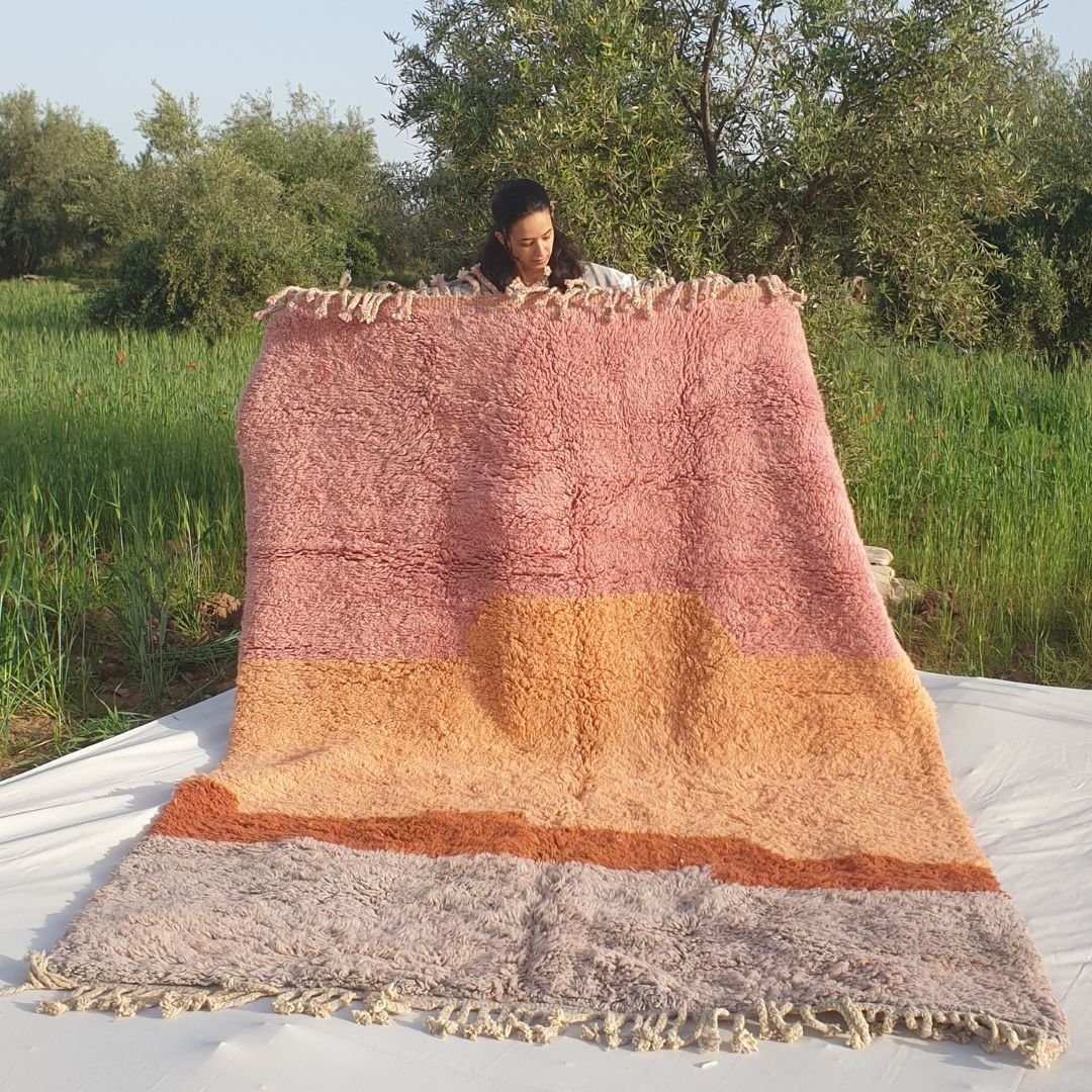 Handwoven 6x9 Beni Mrirt Moroccan rug with abstract pastel pink, orange, and beige color blocks held outdoors in grassy field