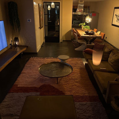 Beautiful terracotta peach lavender sunset gradient shag Beni Mrirt Moroccan rug held outdoors by artisan and styled in warm living room – ultra thick fluffy wool Berber carpet with fringe