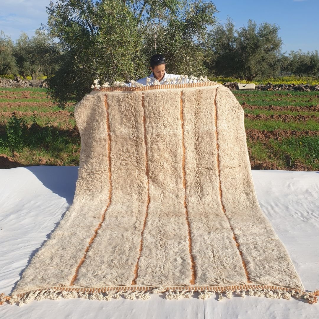 Soft 6x9 Beni Ourain Moroccan rug in ivory with warm orange vertical lines and ultra thick plush pile held outdoors