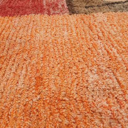 Close-up of a Macla Moroccan rug showing the soft wool pile with the bold dark line art composition - the crossing angular lines forming an abstract figure against the ivory field, with a maroon triangle and pink triangle accent visible nearby, handwoven in 100% wool
