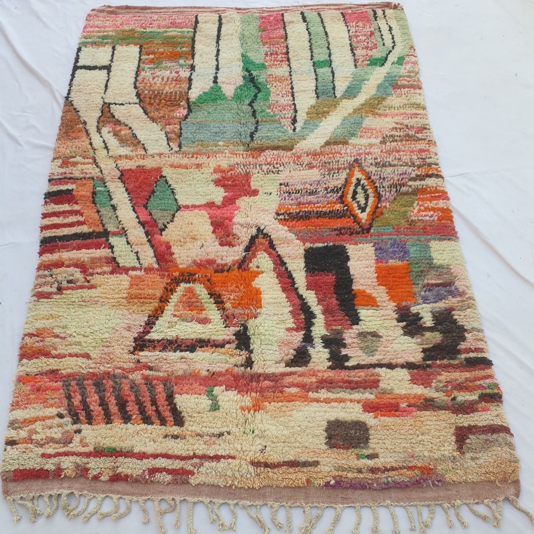 Oueca – handwoven Boujad Berber rug (197x296 cm) laid flat, featuring warm terracotta, cream, and orange abstract tribal composition with geometric triangles and diamonds.