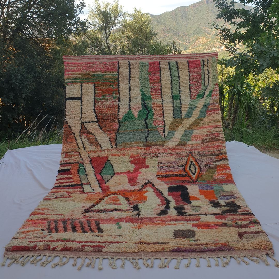 large warm terracotta and cream Boujad Moroccan rug held up in nature, showing bold tribal triangles and diamond motifs.