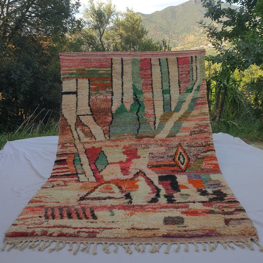 large warm terracotta and cream Boujad Moroccan rug held up in nature, showing bold tribal triangles and diamond motifs.