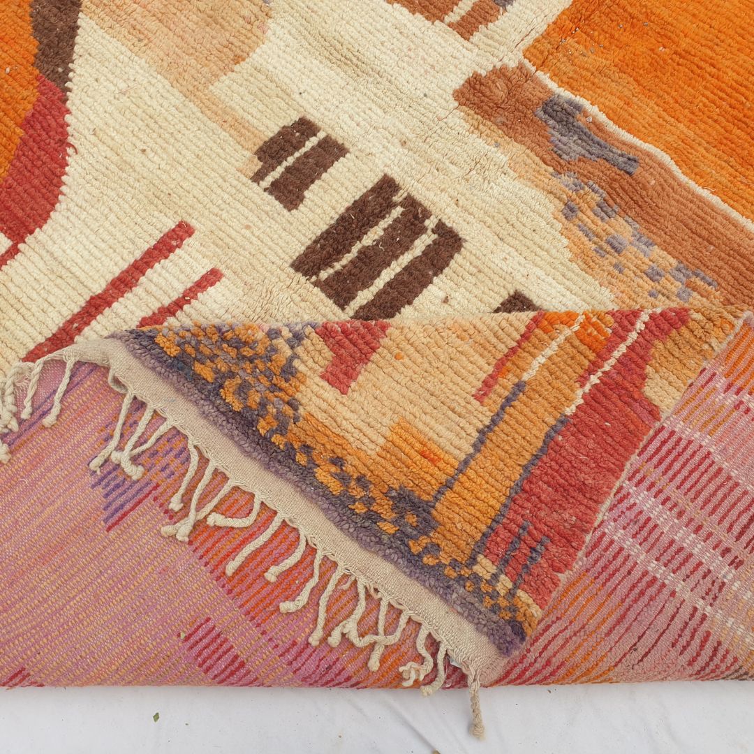 Hand-knotted fringe and detailed border in warm earthy tones framing the bold vibrant geometric tribal design on 9x12 large Boujad Moroccan rug