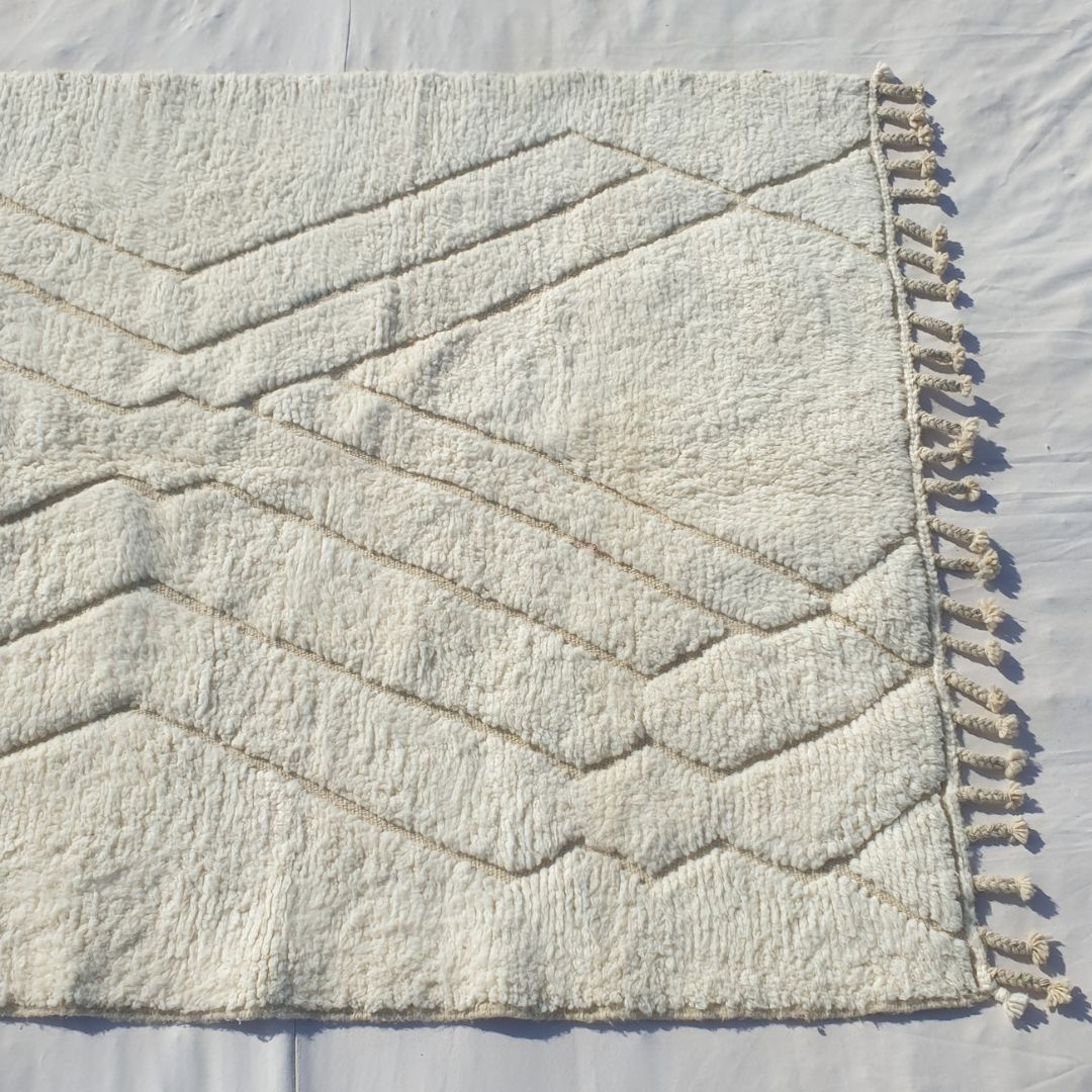 Repeating beige taupe chevron zigzag V rows forming geometric grid on white field of authentic Beni Ourain Moroccan wool rug