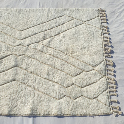 Repeating beige taupe chevron zigzag V rows forming geometric grid on white field of authentic Beni Ourain Moroccan wool rug