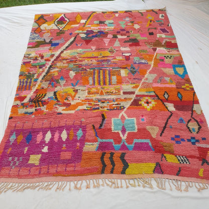 Authentic Boujad Moroccan rug 293×386 cm laid flat — warm coral salmon-pink background densely covered with all-over multicolor geometric motifs including diamonds, zigzags, stripes and triangles in orange, yellow, teal, purple, blue and green, handmade in Morocco by Berber women