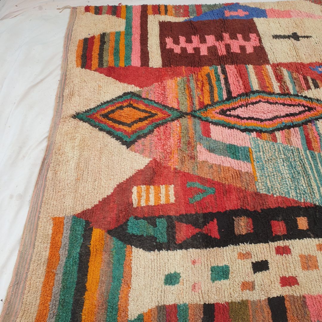 Bottom half of a luxurious cream Moroccan wool rug featuring a dense handknotted pile with vibrant multicolor abstract motifs in blue, orange and red, with natural fringe — showcasing the soft thick texture of authentic Berber craftsmanship
