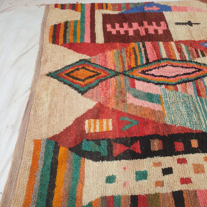 Bottom half of a luxurious cream Moroccan wool rug featuring a dense handknotted pile with vibrant multicolor abstract motifs in blue, orange and red, with natural fringe — showcasing the soft thick texture of authentic Berber craftsmanship
