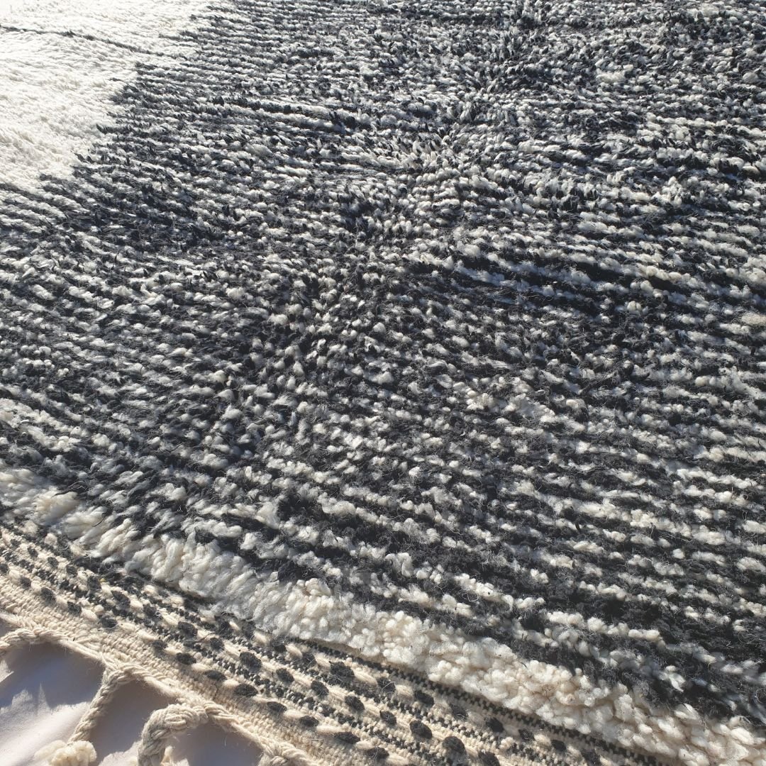 Detailed asymmetrical black geometric motifs and freeform lines on authentic Beni Ourain wool rug, showcasing traditional Berber tribal design