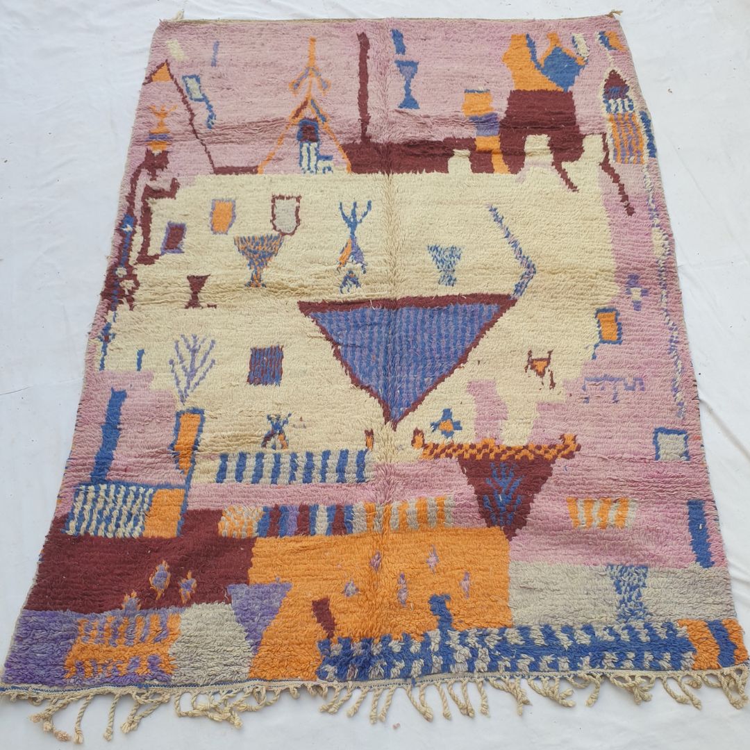 handwoven Boujad Berber rug (201x294 cm) laid flat, dusty pink border with ivory central field, large inverted blue triangle, figurative symbols and vivid lower colour blocks.