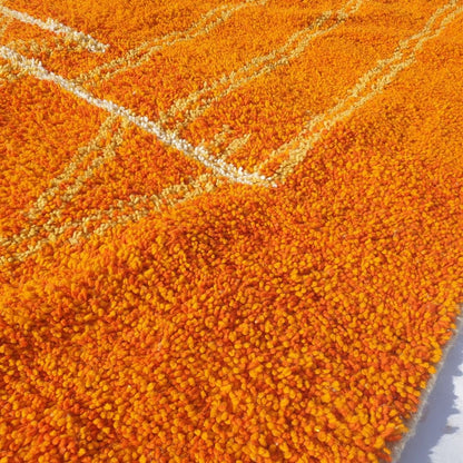 Detailed yellow geometric motifs including triangles, lines, and abstract shapes on the orange field of this Berber Boujad carpet