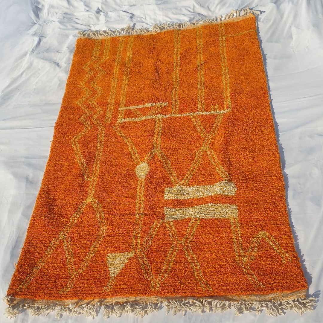 Full view of 6x10 Boujad rug with fringed edges and symmetrical abstract geometric design in orange and yellow tones
