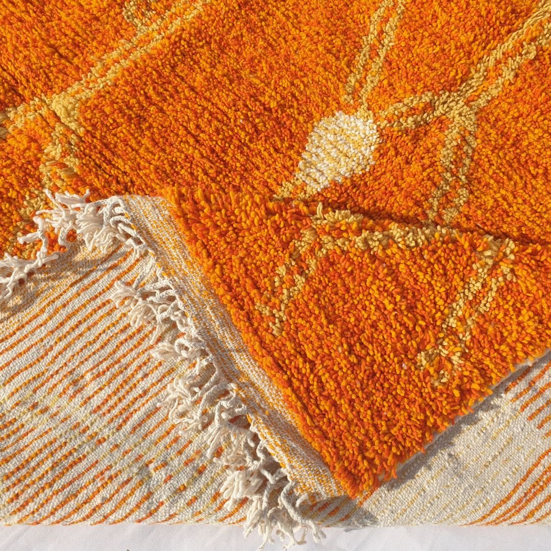 Bold orange background with contrasting yellow tribal patterns highlighting the handwoven craftsmanship of the Boujad rug