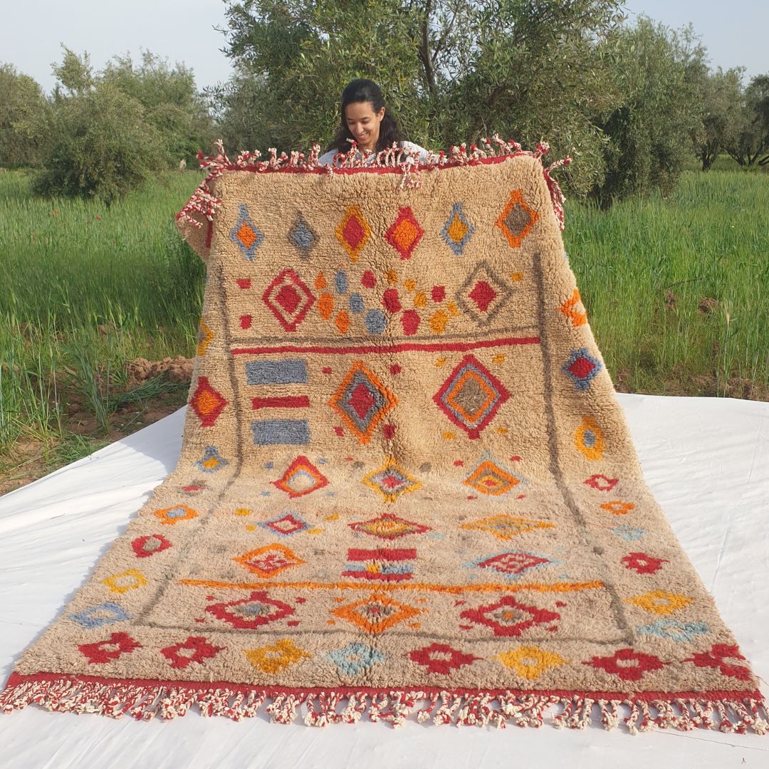 Handwoven 6x9 Beni Mrirt Moroccan rug with vibrant multicolored diamond geometric patterns in red, blue, orange, yellow on beige held outdoors