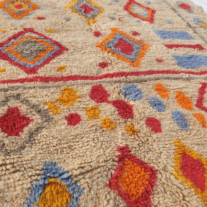 Detailed view of colorful diamond motifs in red, blue, orange, and yellow with gray accents on the beige field of this fluffy Berber Beni Mrirt shag rug